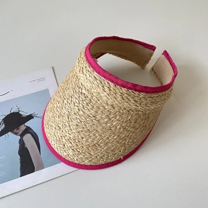 Détail d'un chapeau de soleil en raphia naturel avec bord en tissu fuchsia et texture