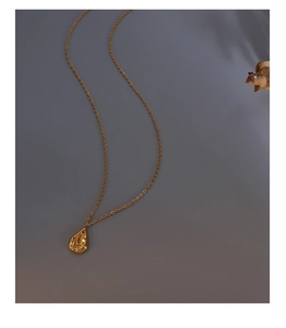 Macro shot of gold teardrop lava pendant with irregular texture on dark background