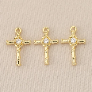 Macro detail of three 18K gold plated Baroque cross pendants with sparkling zircon centers