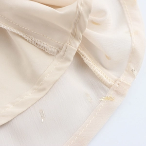 Elegant beige chiffon maxi dress with gold polka dots showing high-quality hem stitching