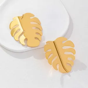 18K gold plated stainless steel monstera leaf earrings on a white ceramic plate