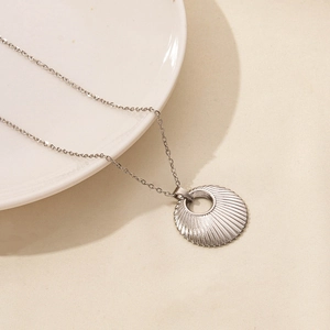 Macro shot of silver sunburst texture pendant and delicate stainless steel chain