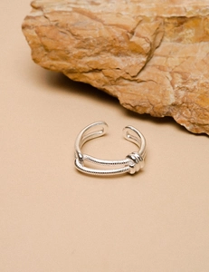 Close-up of double-layered knotted 925 sterling silver ring on a textured natural stone