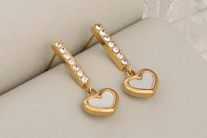 Detailed view of gold heart drop earrings with white shell inlay and sparkling rhinestones