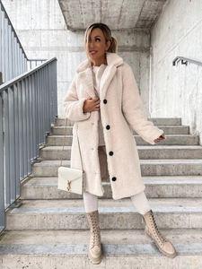 Detail of plush cream teddy coat featuring wide lapels and contrasting black buttons