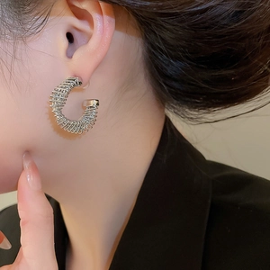 Detailed close-up of a silver-plated twisted spring C-shaped hoop earring on a model