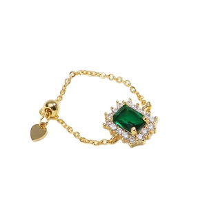 Adjustable gold chain ring with rectangular emerald gemstone and heart pendant detail