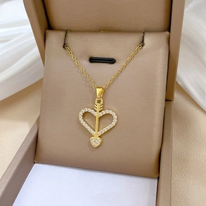 Macro view of gold heart and arrow pendant with sparkling cubic zirconia on silk