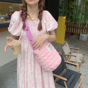 Détail du sac bandoulière rose matelassé en cœurs avec sangle violette et étiquette