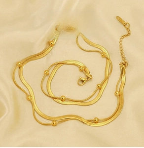 Detailed shot of double-layer gold stainless steel snake chain necklace on silk background