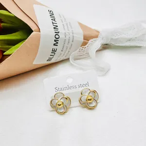 Detail of camellia earrings with white enamel petals and gold heart on a tulip background