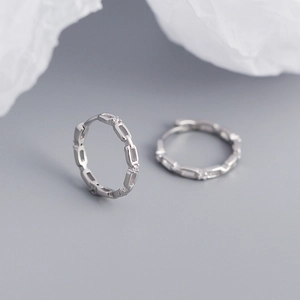Macro shot of silver geometric chain earrings with embedded small sparkling gemstones