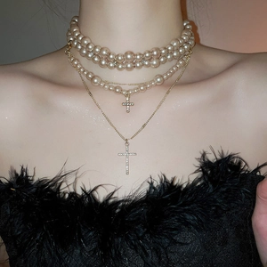 Detail view of multi-layered pearl necklaces with sparkling rhinestone cross pendants