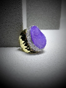 Detail of a gold hammered ring with a large purple crystal cluster and zircon accents