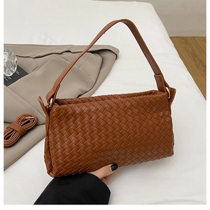 Détail du sac tressé en cuir marron avec bandoulière et style urbain minimaliste