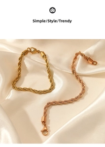 Detail of twisted rope chain bracelets in gold and rose gold on white silk fabric