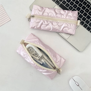 Close-up of pink quilted PU pencil case with heart and bow patterns for stationery storage