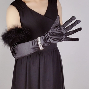 Detail of long black satin gloves featuring elegant feather trim and a rhinestone bracelet