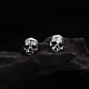 Macro detail of high-polish silver skull studs on dark textured wooden background