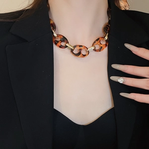 Dettaglio della collana a catena in tartaruga e oro indossata da una modella