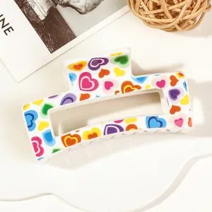Macro shot of white acrylic hair claw clip with colorful heart patterns for hair styling