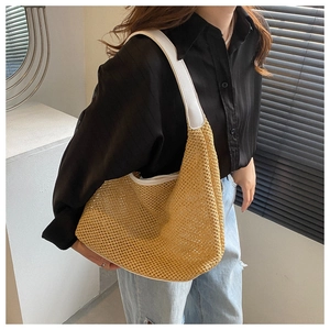 Detail of khaki hollow woven straw bag featuring white PU leather trim and wide shoulder strap