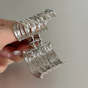 Detail of silver hollow metal hair claw clip with vintage style held by hand