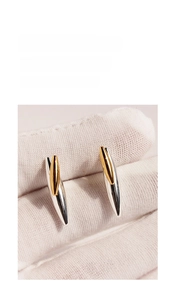 Macro shot of two-tone gold and silver rivet stud earrings with a sharp cone design