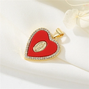 Detail of a 14K gold heart pendant with red inlay and cubic zirconia on white silk