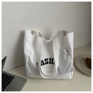 Detailed shot of white canvas tote bag with FASHION print and matching mini pouch