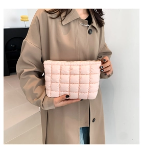 Detail of pink quilted puffer handbag held by model wearing a beige trench coat