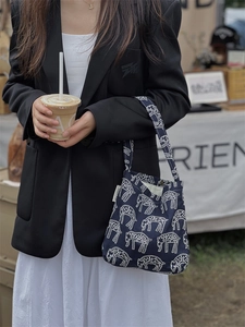 Detail of navy blue canvas bag with white sheep print shown in a street style look