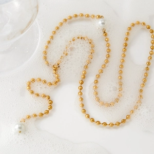 Elegant gold beaded Y-shaped stainless steel necklace featuring white pearls on a foam background