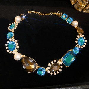 Close-up of vintage gold necklace with blue and brown gemstones and white pearls