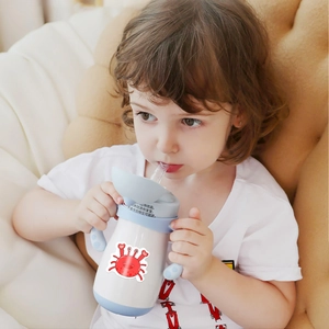 Toddler using white baby straw cup with light blue handles and red crab illustration