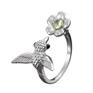 Macro detail of hummingbirds and flowers with green gemstone on silver open ring
