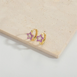 Golden star hoop earrings with purple enamel and zircon detail on marble surface