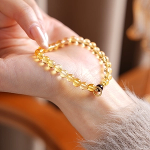 Macro shot of citrine beads bracelet with golden charm pendant and brown garnet bead