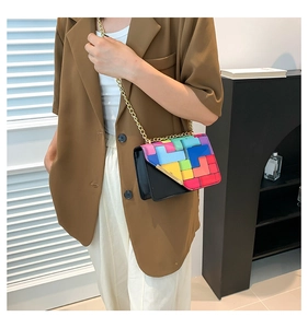 Detail of color-block flap bag with geometric puzzle patterns and gold chain strap