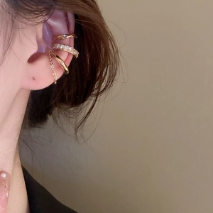 Close-up of golden multi-layer ear cuffs with zircons and chain tassel details