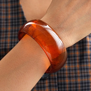 Detailed macro view of amber resin bangle showing natural swirled patterns and texture