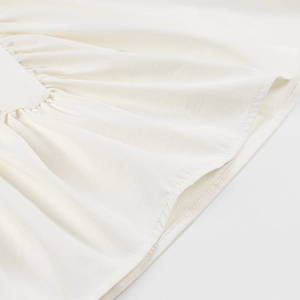 Close-up of the fine texture and pleated stitching on a beige summer sleeveless top