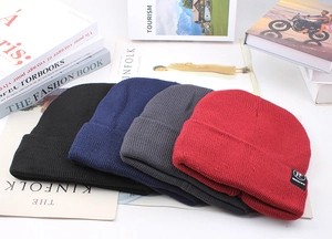 Flat lay detail of knitted beanies in black, navy, grey, and red with woven label