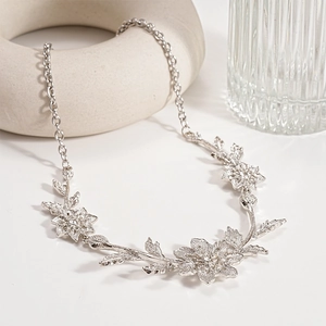 Close-up of silver-tone floral leaf necklace with sparkling zircon crystals and textured metal