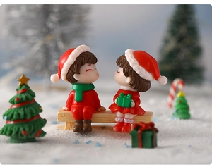 Close-up of Christmas couple figurines sitting on a wooden bench in snowy scenery