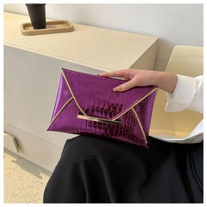 Detail of purple envelope clutch bag featuring metallic crocodile texture and gold hardware