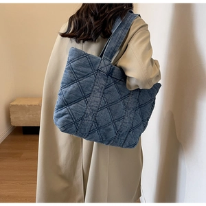 Détail du sac cabas en denim matelassé porté avec un trench-coat beige élégant