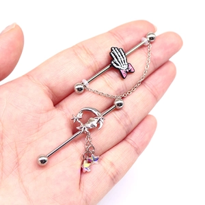 Detail of silver industrial barbell earrings with butterfly and star pendants