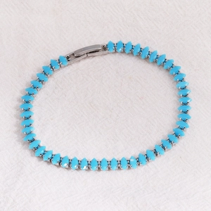 Macro view of blue marquise-cut stones set in silver tennis bracelet with secure fold-over clasp