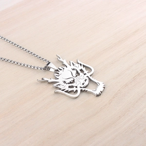 Close-up of stainless steel dragon head pendant with box chain on wood surface